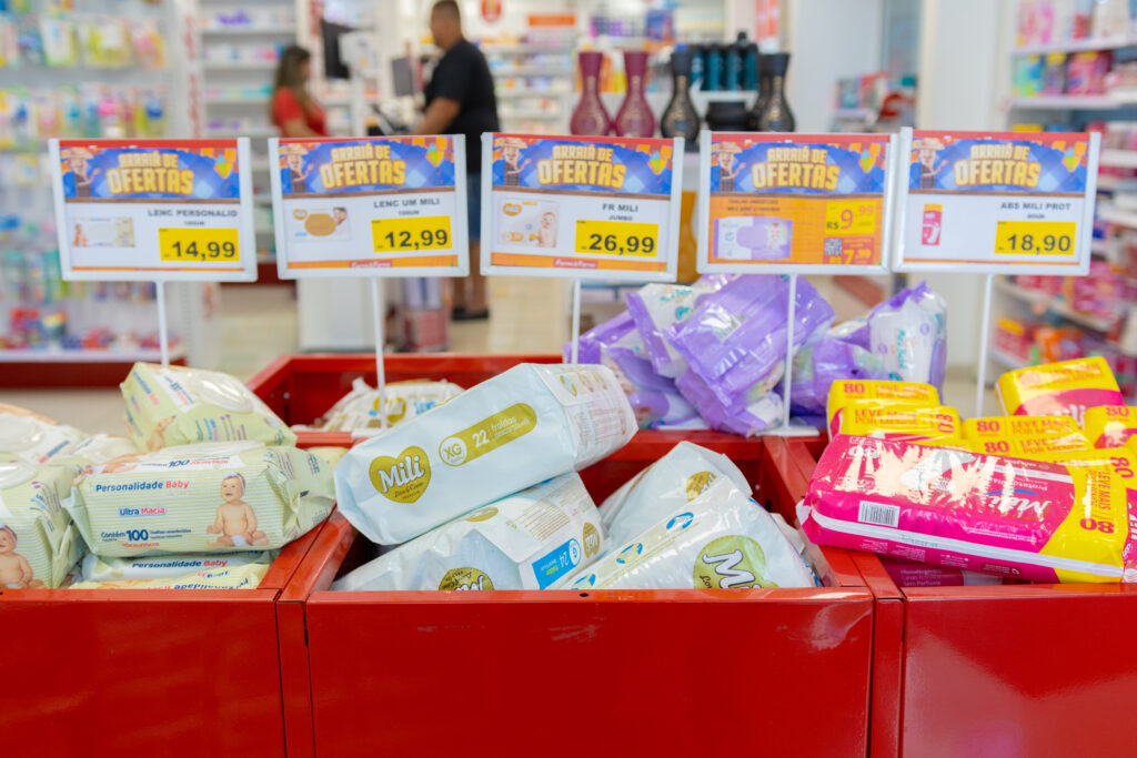 Cestão de ofertas com fraldas, lenços umedecidos e absorventes em promoção na farmácia Farma e Farma