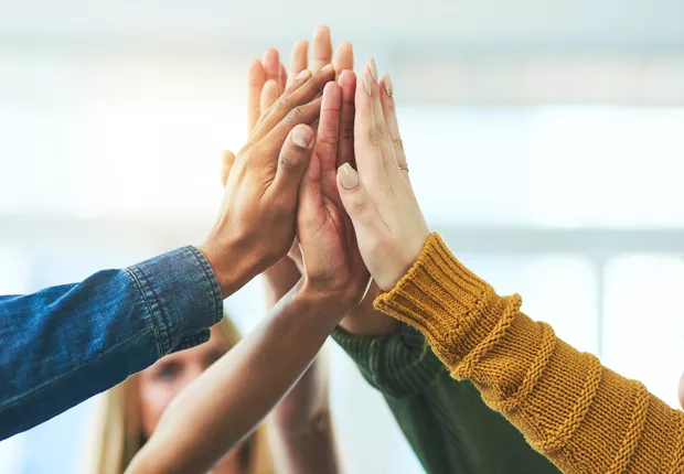 Mãos unidas em gesto de celebração, simbolizando trabalho em equipe, parceria e sucesso coletivo nas Células da Farma e Farma.