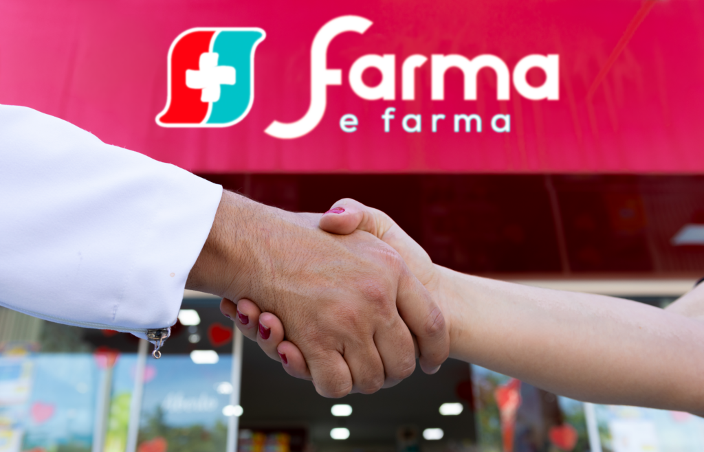 Mãos se cumprimentando em frente à unidade Farma e Farma, indicando parceria entre franqueado e franqueadora.