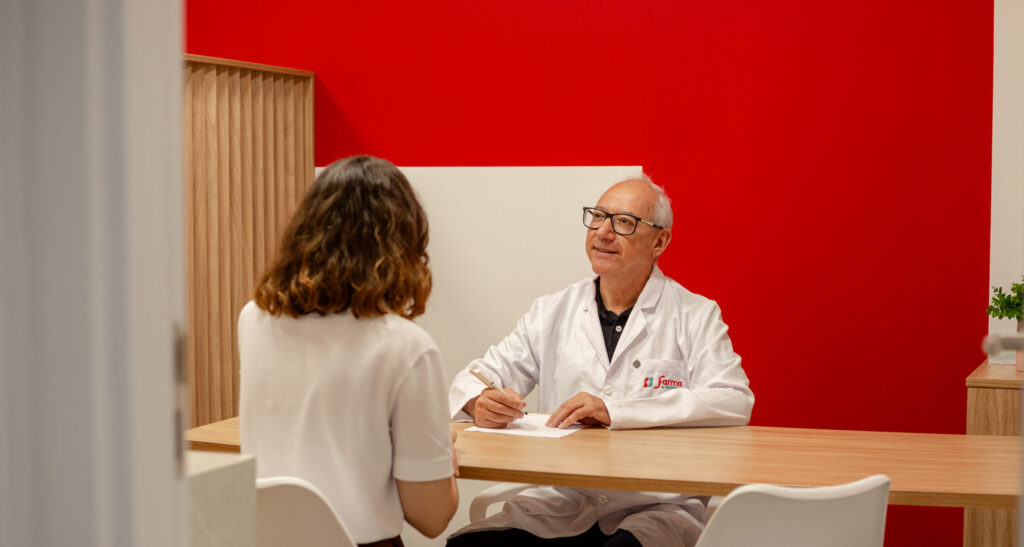 Farmacêutico realizando atendimento consultivo em sala clínica dentro de farmácia, orientando paciente sobre cuidados de saúde