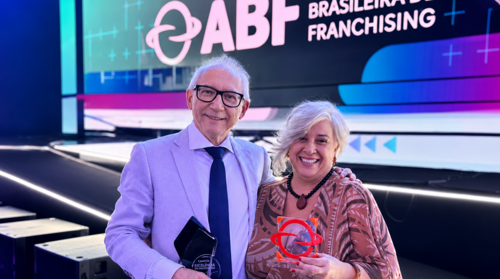 Rinaldo Ferreira e Liege Bernardo de Almeida seguram o Selo de Excelência em Franchising da ABF e o Prêmio ESG na categoria Governança durante cerimônia da Associação Brasileira de Franchising.
