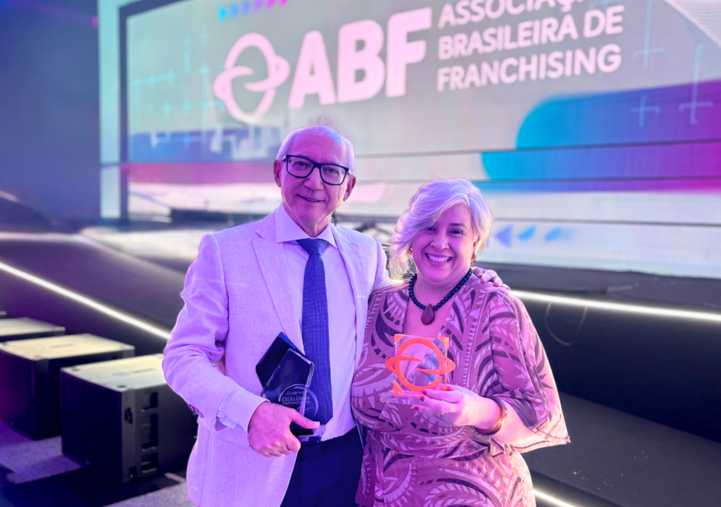 Rinaldo Ferreira e Liege Bernardo de Almeida seguram o Selo de Excelência em Franchising da ABF e o Prêmio ESG na categoria Governança durante cerimônia da Associação Brasileira de Franchising.
